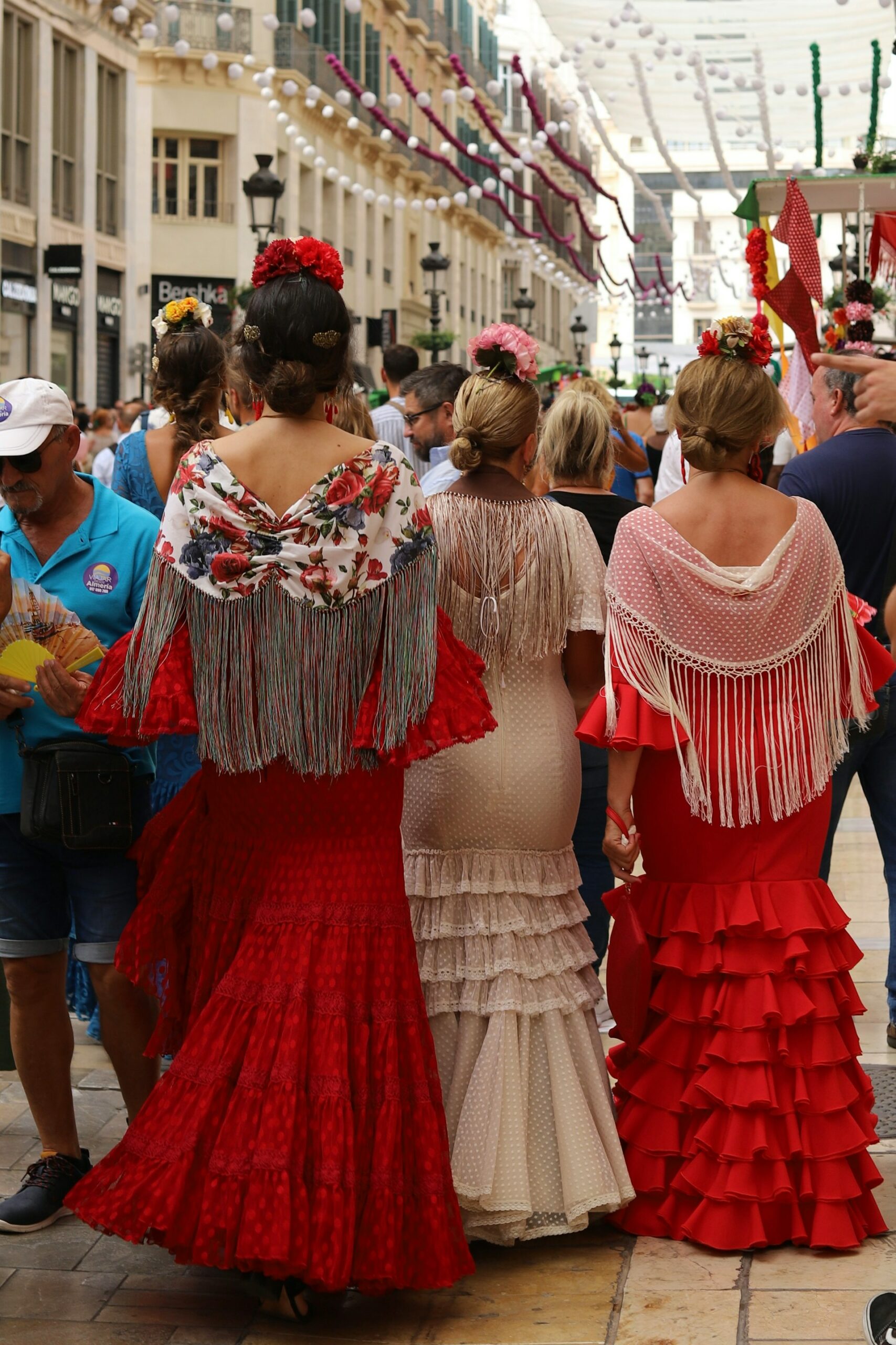 Jeunes femmes de dos en habits traditionnels andalous à Malaga, illustrant l’authenticité et la richesse culturelle d’un voyage immersif sur-mesure en Espagne.