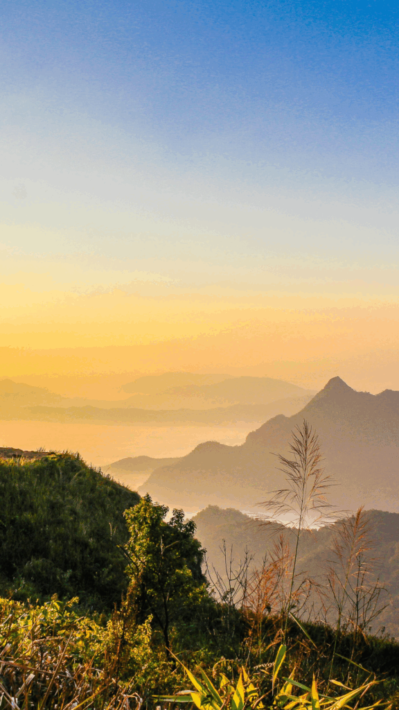 Vue au sommet d’une montagne en Thaïlande au coucher du soleil, entre brume et lumière, invitation au voyage intérieur. Récit d'un voyage immersif et sur-mesure.